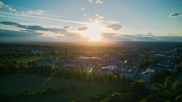 Aerial view of a cityscape at sunset with sun rays piercing through clouds, highlighting green spaces and urban buildings in Harrogate, North Yorkshire. photo