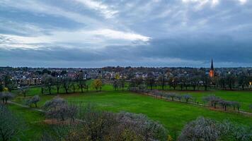 escénico ver de un lozano verde parque con un ciudad horizonte debajo un dramático nublado cielo a oscuridad en Harrogate, norte yorkshire. foto