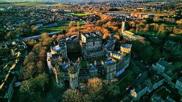 Aerial view of a majestic Lancaster castle surrounded by greenery with a town in the background during sunset. photo