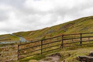 Rustic wooden fence leading into rolling green hills under a cloudy sky, depicting tranquil rural landscape in Yorkshire Dales. photo
