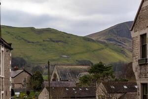 Quaint village with traditional houses against rolling green hills under a cloudy sky. photo