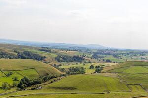 Serene rolling hills with lush green fields under a clear sky, depicting tranquil rural landscape. photo