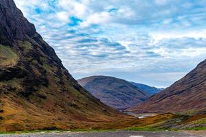 Scenic view of a mountain pass with lush green slopes under a blue sky with clouds. photo