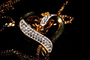 Elegant gold and diamond heart-shaped pendant on a dark background with a soft focus on the jewelry's texture. photo