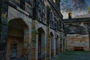 Historic stone building with archways under a dramatic sky at dusk in Lancaster. photo