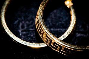 Elegant gold bracelet with intricate patterns on a dark background. photo