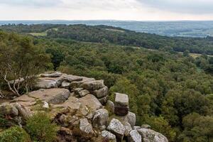 Scenic view of a rocky outcrop overlooking a lush forest valley with overcast skies. photo