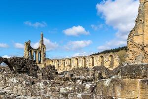 Ancient ruins under blue sky with clouds, historical architecture with arches and columns in Yorkshire. photo