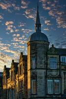 Historic stone building with a spire against a dramatic sky with golden sunset clouds in Lancaster. photo