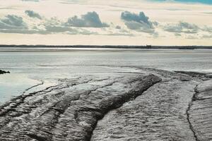 Serene coastal landscape with textured tidal patterns and a cloudy sky. photo