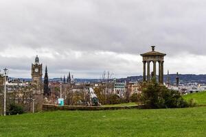 Panoramic view of Edinburgh skyline with historic monuments and green landscape, cloudy sky. photo