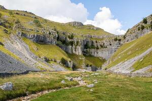 Scenic limestone cliffs with grassy slopes and rocky terrain under a cloudy sky in a mountainous region. photo