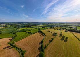 Aerial view of a lush countryside with patchwork fields under a blue sky with wispy clouds. photo