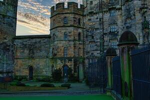 Historic stone castle at dusk with dramatic sky and greenery, suitable for travel and history themes in Lancaster. photo