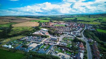 Aerial view of a quaint village with traditional houses, surrounded by green fields and open countryside under a cloudy sky in Staithes, England. photo