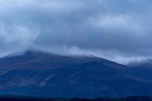 Misty mountain peaks with blue overcast sky in Scotland. photo