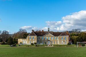 Elegant historical mansion with a lush green lawn under a blue sky with scattered clouds. photo