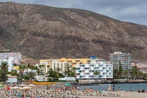 Tenerife beach with tourists and mountain backdrop photo