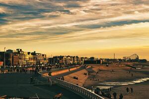 Golden sunset over a bustling beach promenade with silhouettes of people and modern buildings in Blackpool, England. photo