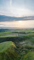 Scenic vertical landscape with rolling hills and a sunset over a tranquil countryside. photo