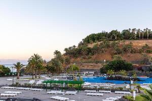 Serene resort with swimming pools surrounded by palm trees at the foot of a lush hill during twilight in Santa Cruz de Tenerife photo