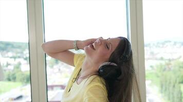 joven atractivo mujer vistiendo auriculares escuchando música y bailando a hogar video