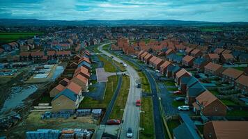 Aerial view of a suburban neighborhood with rows of houses and a winding road, under a cloudy sky. photo