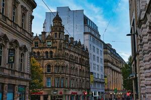 Dusk view of a bustling city street with historic architecture and glowing street lights under a blue sky in Manchester, England. photo