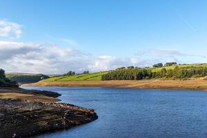 Serene lake with lush green hills under a clear blue sky. photo