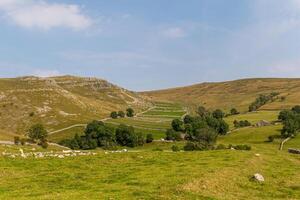 Idyllic rural landscape with rolling hills, green fields, and clear blue sky, perfect for background or nature themes. photo