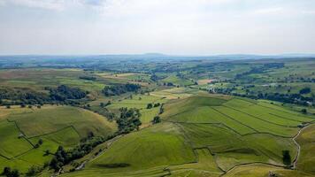 Aerial view of lush green countryside with patchwork fields and meandering roads under a hazy sky. photo