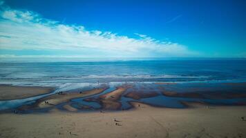 Aerial view of a tranquil beach with patterns in the sand, gentle waves, and a clear blue sky in Backpool, England. photo