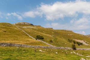 Sunny landscape of rolling hills with dry stone walls and a clear blue sky. photo