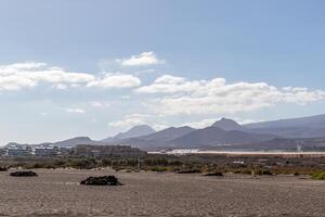 Scenic view of a desert landscape with mountain range in the background under a clear blue sky in Tenerife. photo