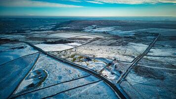 Aerial view of a snowy landscape with roads intersecting under a blue sky at dusk. photo