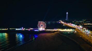 Nighttime aerial view of a lit Ferris wheel and pier with city lights along the beachfront in Backpool, England. photo