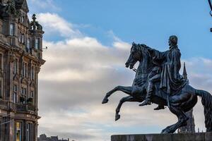 Equestrian statue silhouette against a cloudy sky, with historic architecture in the background in Edinburgh, Scotland. photo