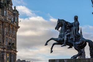 ecuestre estatua silueta en contra un nublado cielo, con histórico arquitectura en el antecedentes en Edimburgo, Escocia. foto