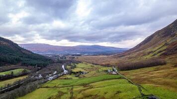 Aerial view of a lush green valley with mountains under a cloudy sky in Scotland. photo