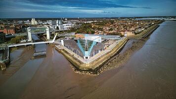 Aerial view of a modern flood barrier on a muddy river near an urban area under a cloudy sky in Hull, England. photo
