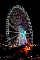 Illuminated Ferris wheel at night with vibrant blue lights against a dark sky. photo