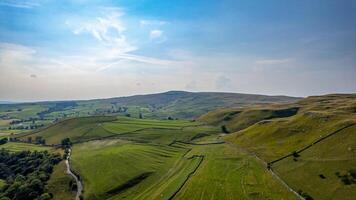 Breathtaking aerial view of green rolling hills and fields under a blue sky with wispy clouds. photo