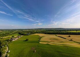 Aerial view of lush green countryside with fields and trees under a blue sky with radiating clouds. photo