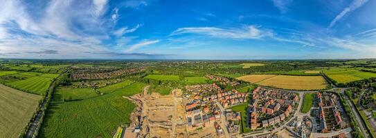 panorámico aéreo ver de un pintoresco pueblo con rodeando verde campos debajo un azul cielo con nubes foto