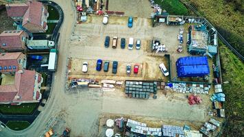 Aerial view of a construction site with materials and vehicles, surrounded by buildings. photo