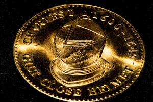 Close-up of a golden coin with intricate details on a dark background. photo