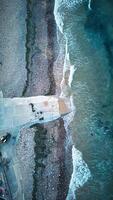 Aerial view of a serene beach with waves gently lapping against a stone pier in Saltburn-by-the-Sea photo