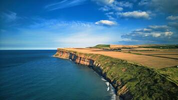 Breathtaking coastal cliffs under a blue sky with scattered clouds, overlooking the ocean in Saltburn-by-the-Sea photo