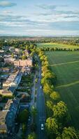 Aerial view of a quaint town with lush green fields under a clear blue sky at sunset in Harrogate, North Yorkshire. photo