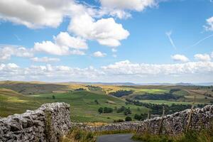 Scenic view of rolling hills and countryside with stone walls under a blue sky with clouds. photo